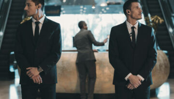 two bodyguards waiting for businessman standing at reception counter