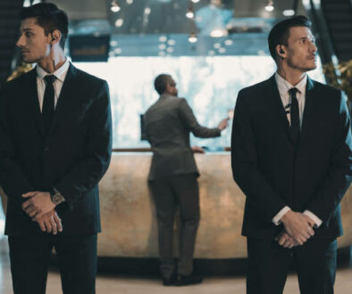 two bodyguards waiting for businessman standing at reception counter